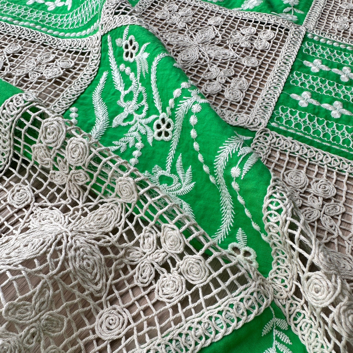 Close-up of green fabric with intricate creamembroidery