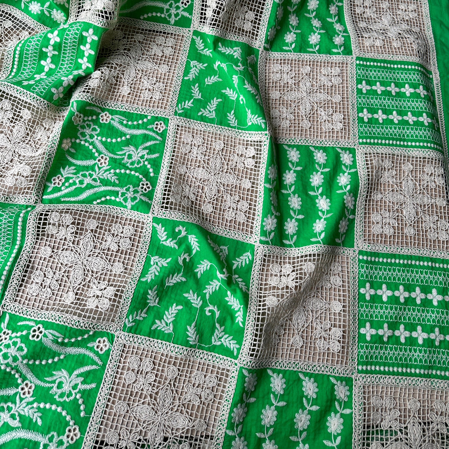 Green patchwork dressmaking fabric with embroidered and crocheted panels