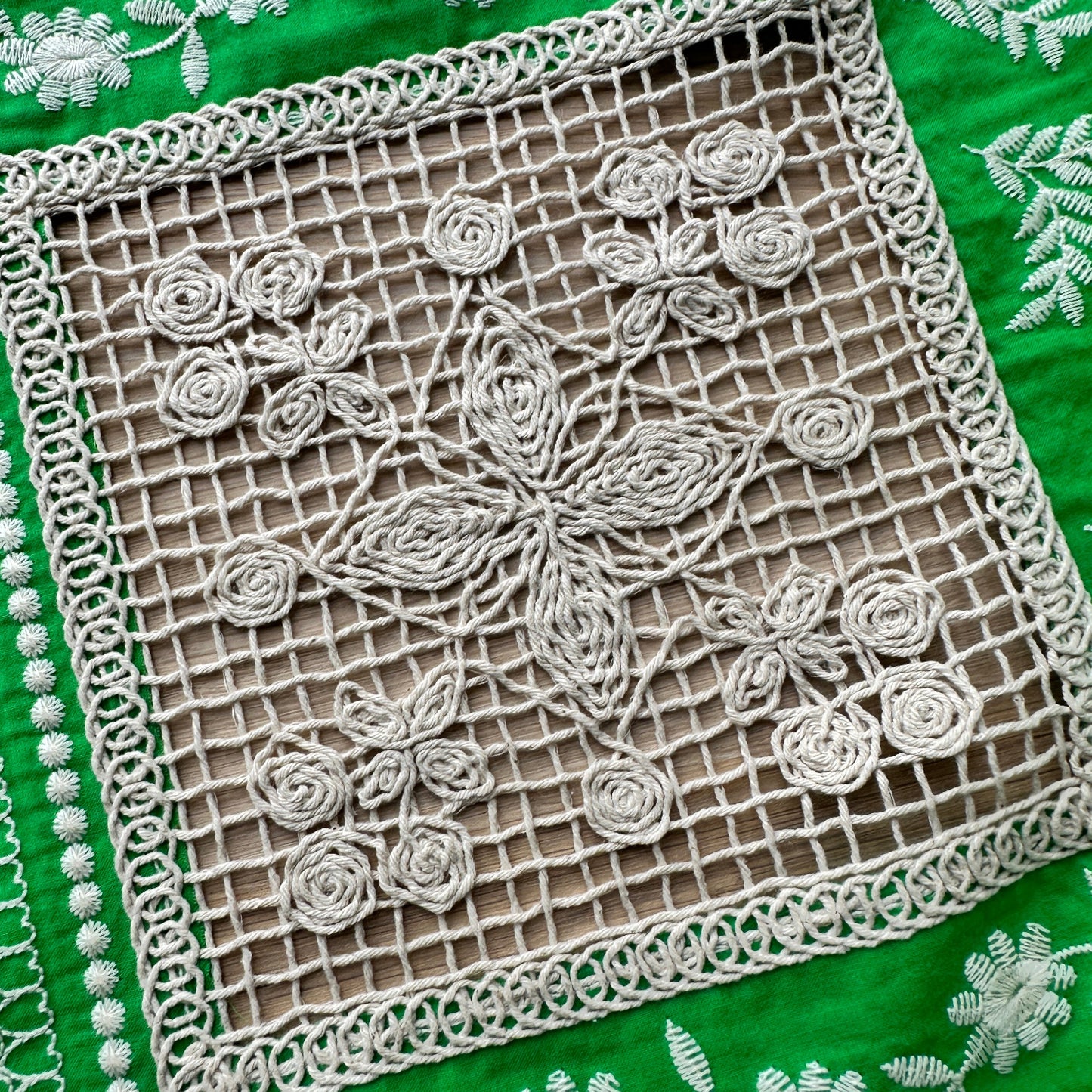 Close-up of a green fabric with cream embroidery