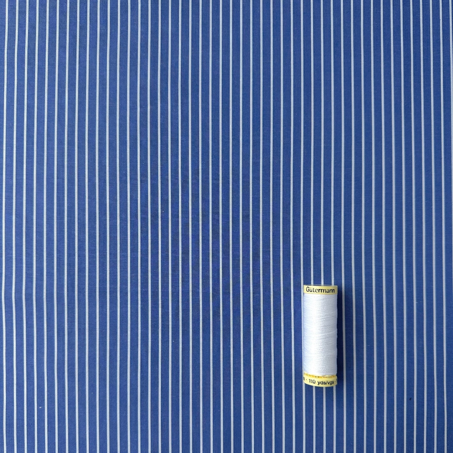Blue and white striped fabric with reel of fabric for scale
