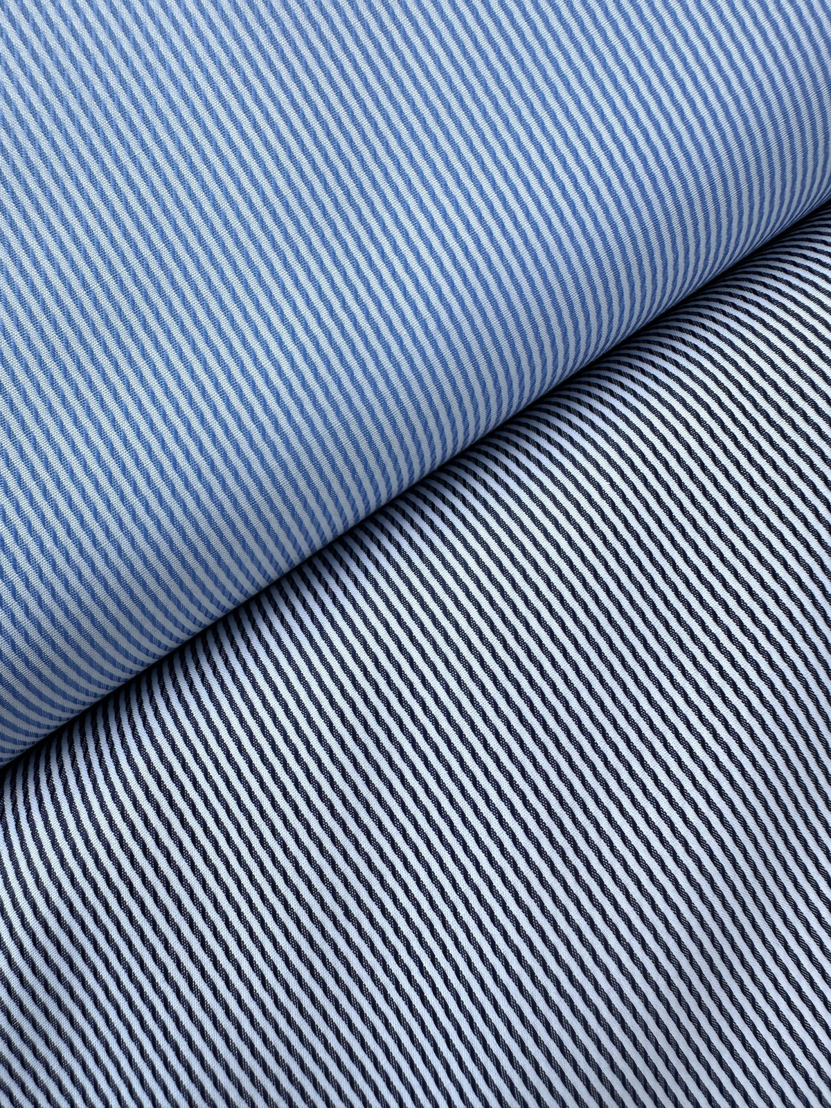 Close-up of two bolts of striped cotton dressmaking fabric, one in navy and white and the other in blue and white