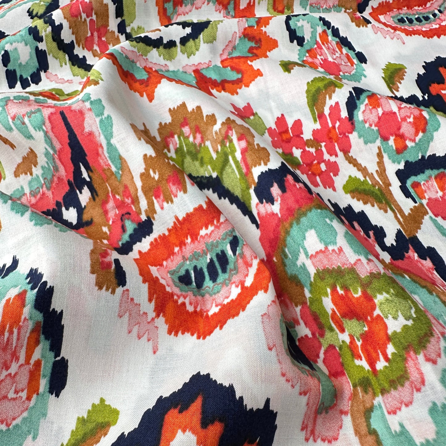 Close up of colourful paisley fabric with an off white background