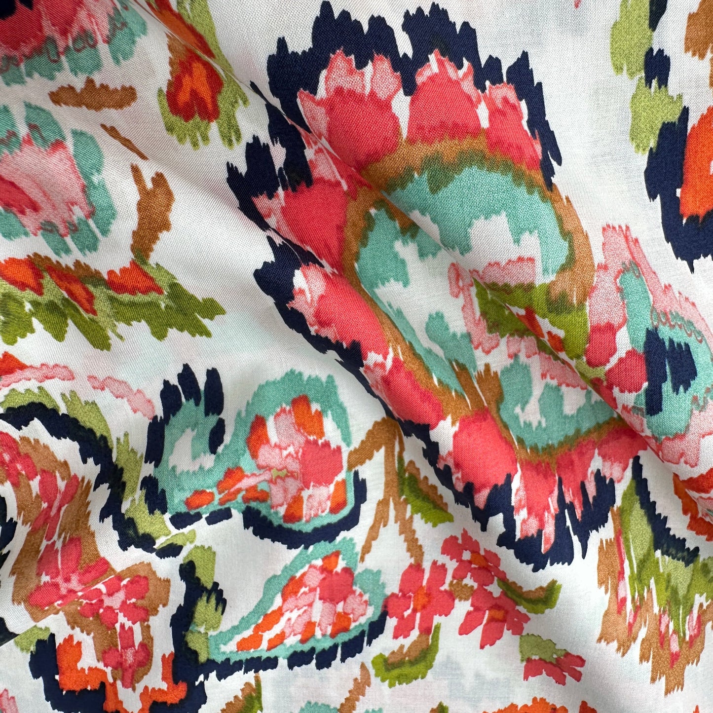 Coral, navy, pink, green and orange paisley pattern across an off white pima cotton lawn fabric