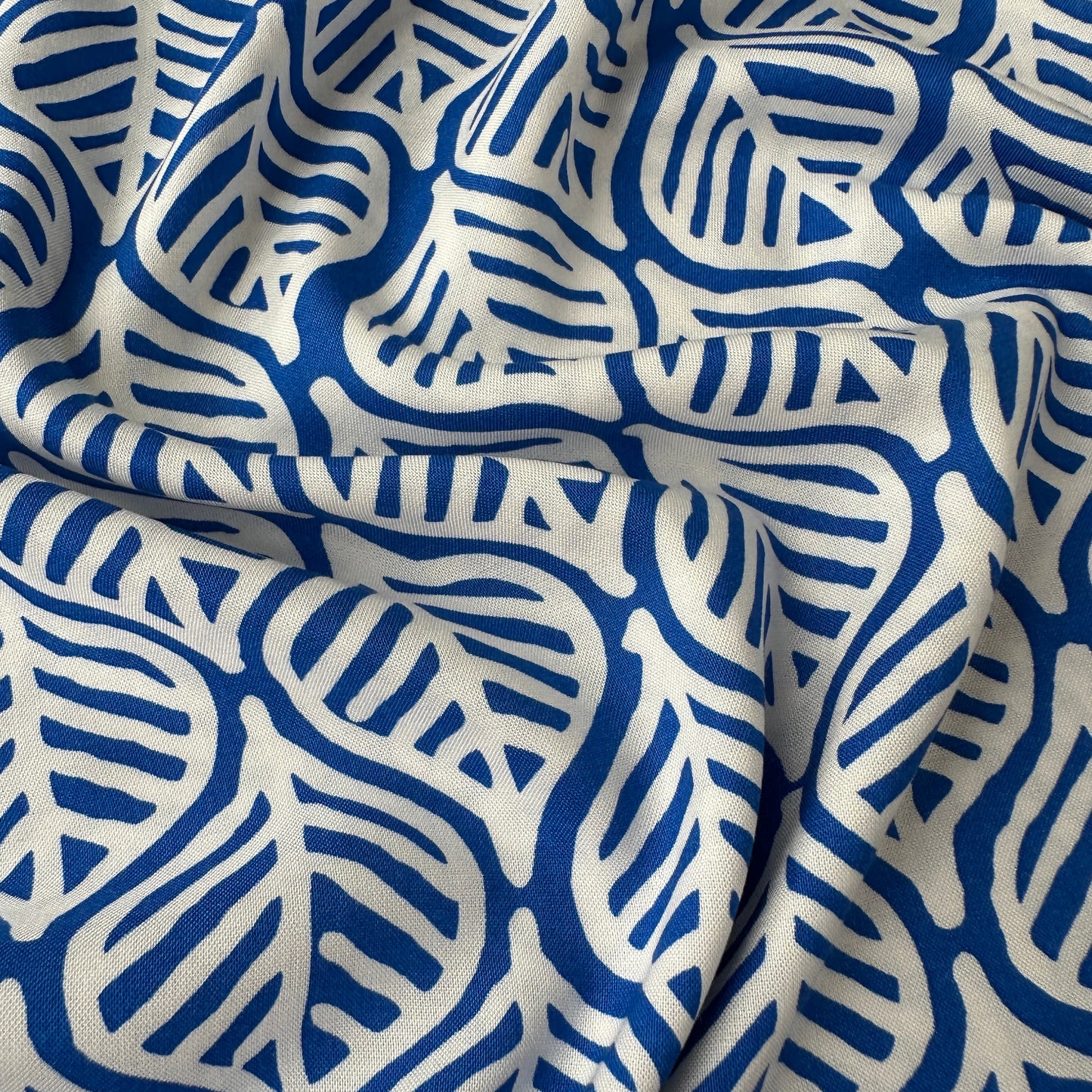 Close up of white leaves on cobalt blue viscose fabric