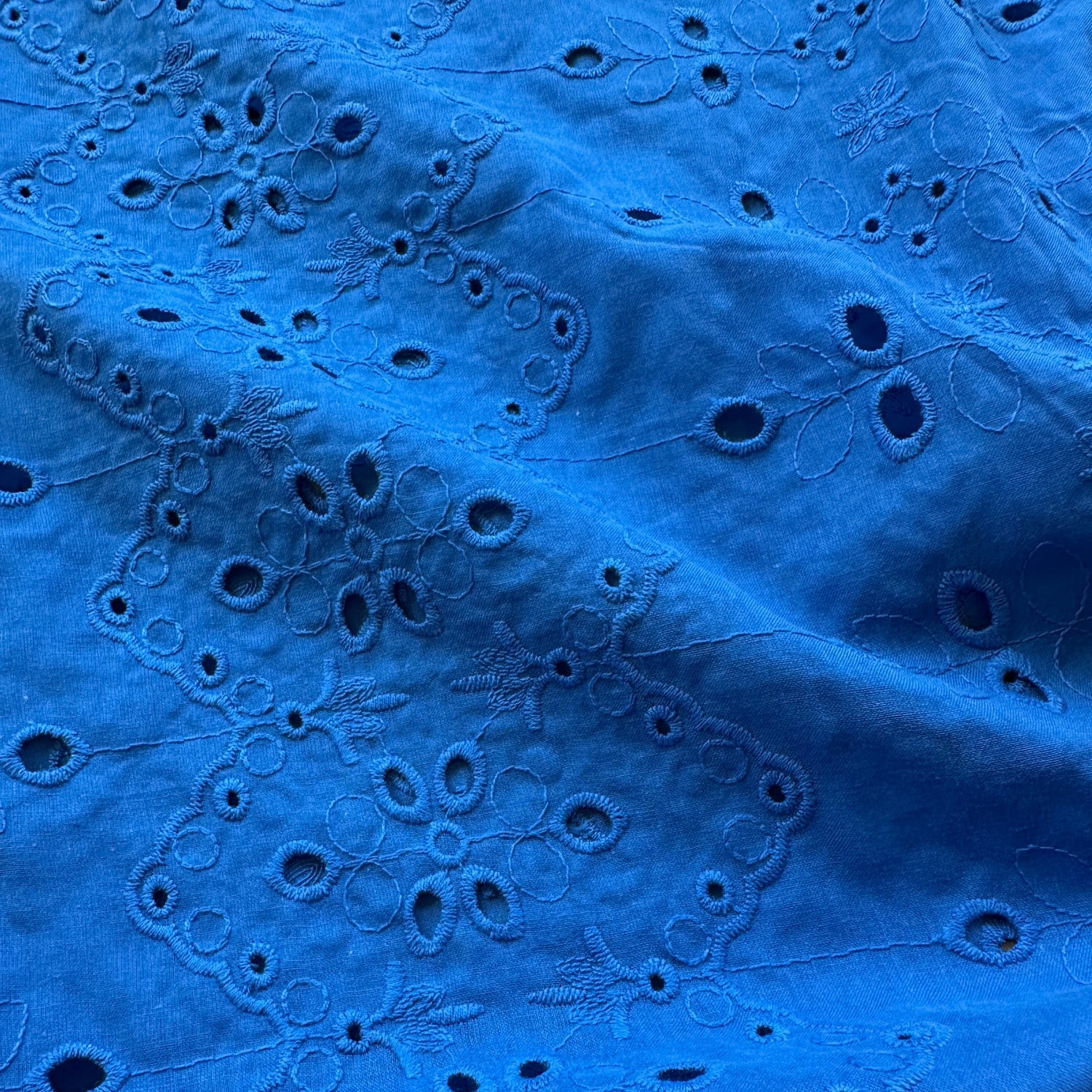 Blue broderie anglaise fabric featuring cut outs and embroidery