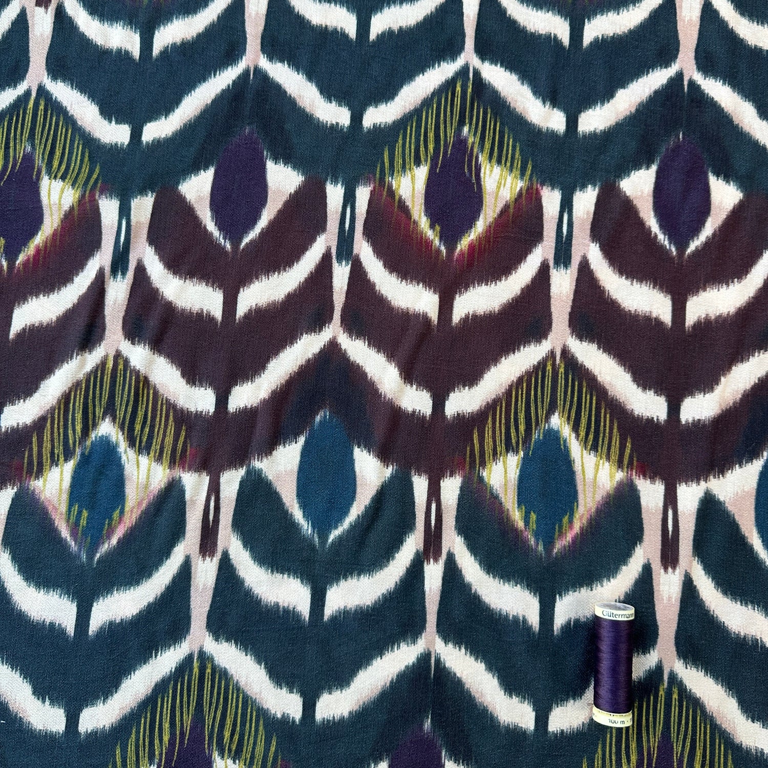 reel of thread for scale on abstract floral viscose blend fabric