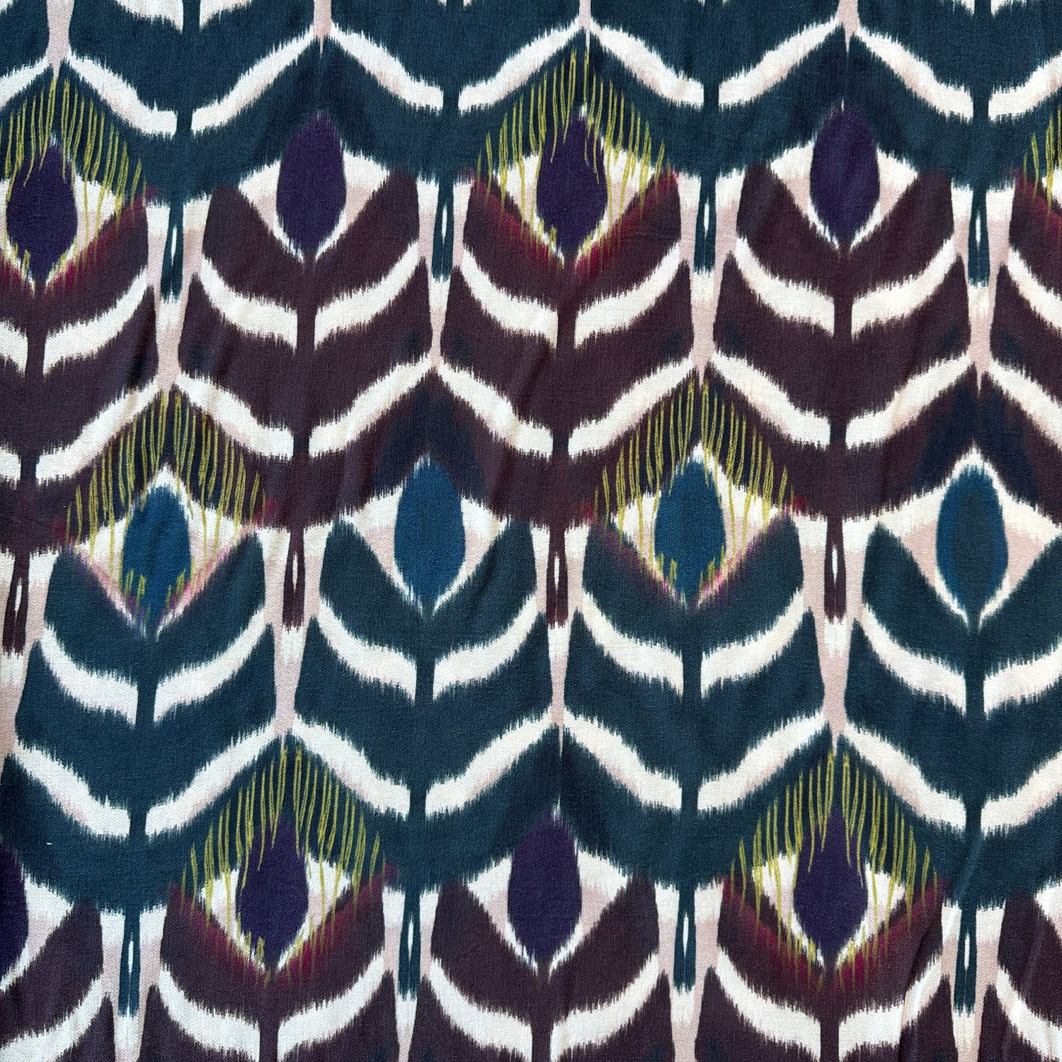 Fabric with repeating pattern of geometric shapes in blue, purple, and green on lighter background