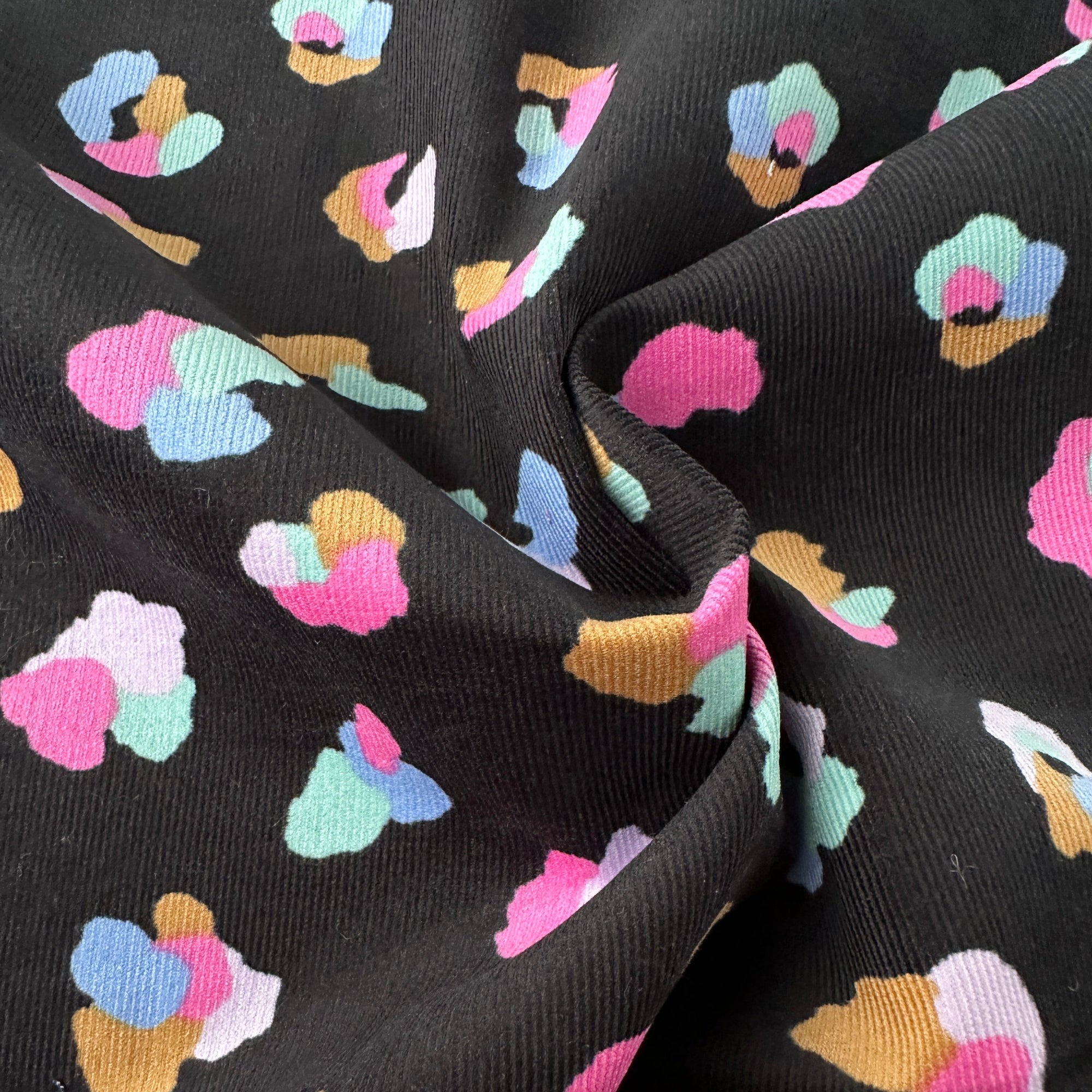 Animal Print Cotton Babycord Fabric in Black in a swirl to show the wales (ridges)