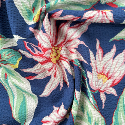 Close-up of floral fabric with pink flowers and green leaves on a blue background