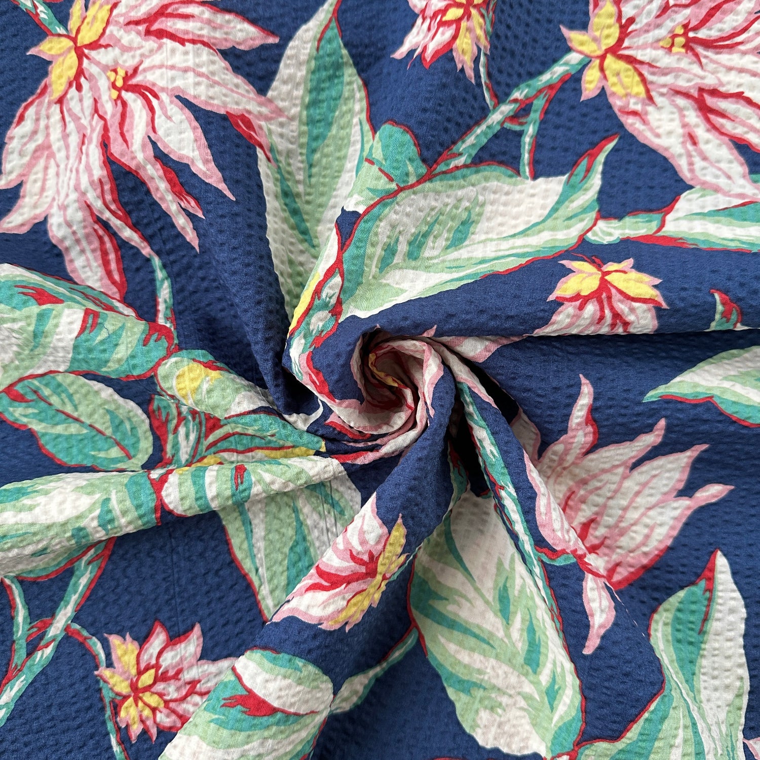 Close-up of floral seersucker fabric with pink flowers and green leaves on a navy background
