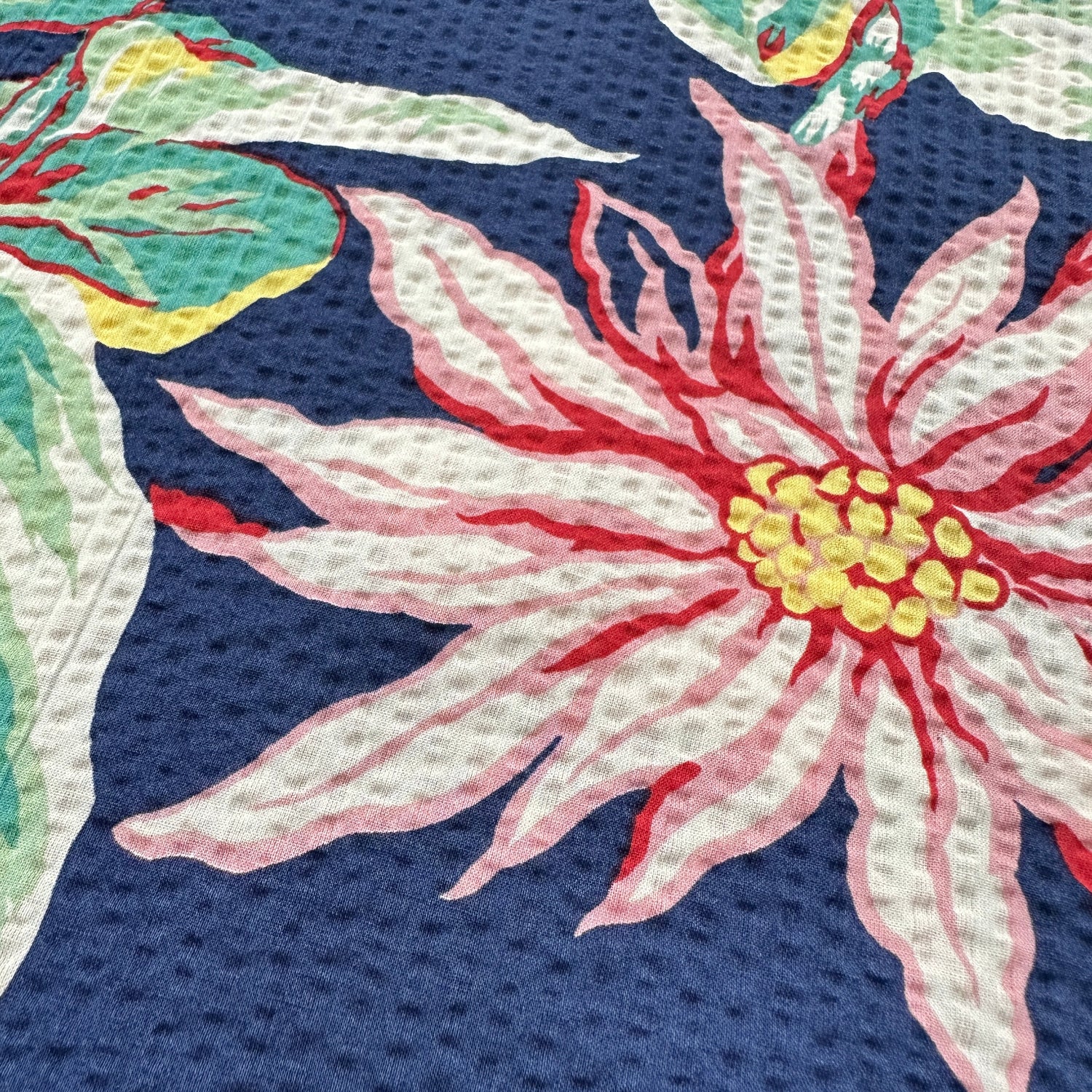 Close-up of a floral fabric 
with pink flowers and green leaves on a blue background