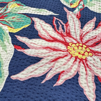 Close-up of a floral fabric 
with pink flowers and green leaves on a blue background