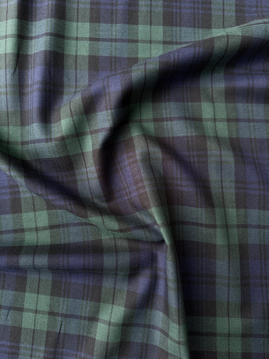 A close-up of draped fabric with a plaid pattern in green, navy and black