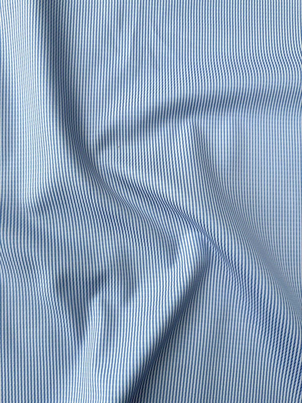 A close-up of light blue and white stripe fabric with soft folds