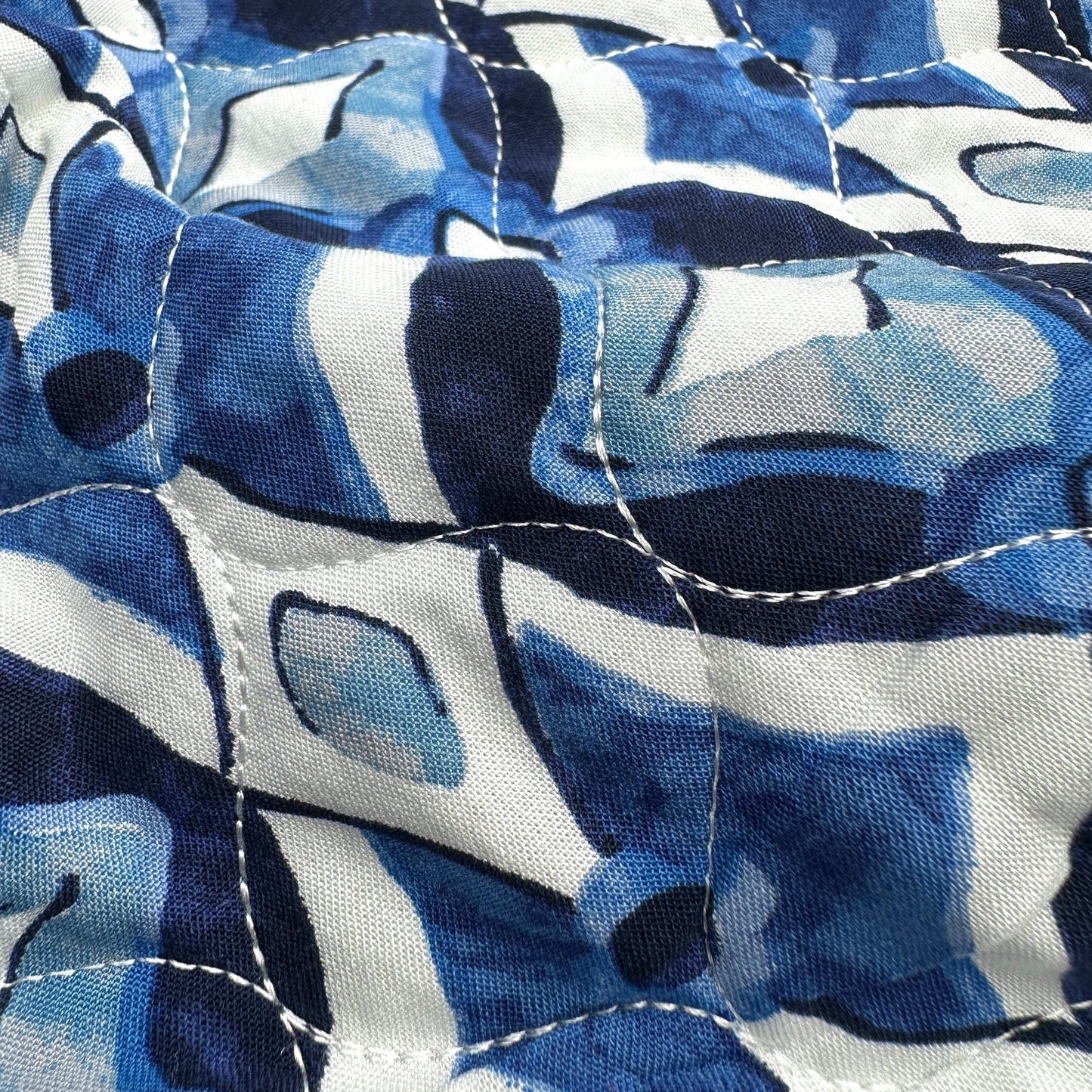 Close up of blue and white patterned fabric with visible stitching