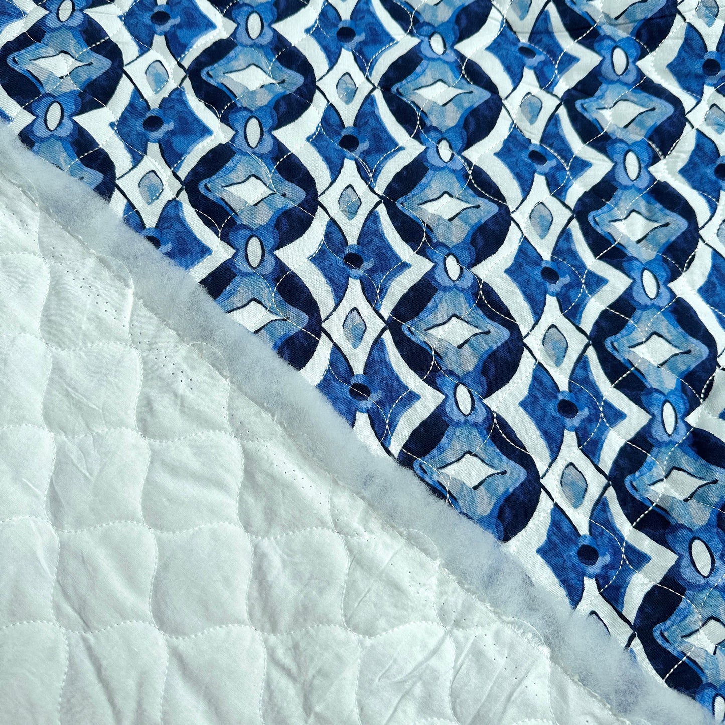 Both sides of quilted fabric with diamonds in blue and white