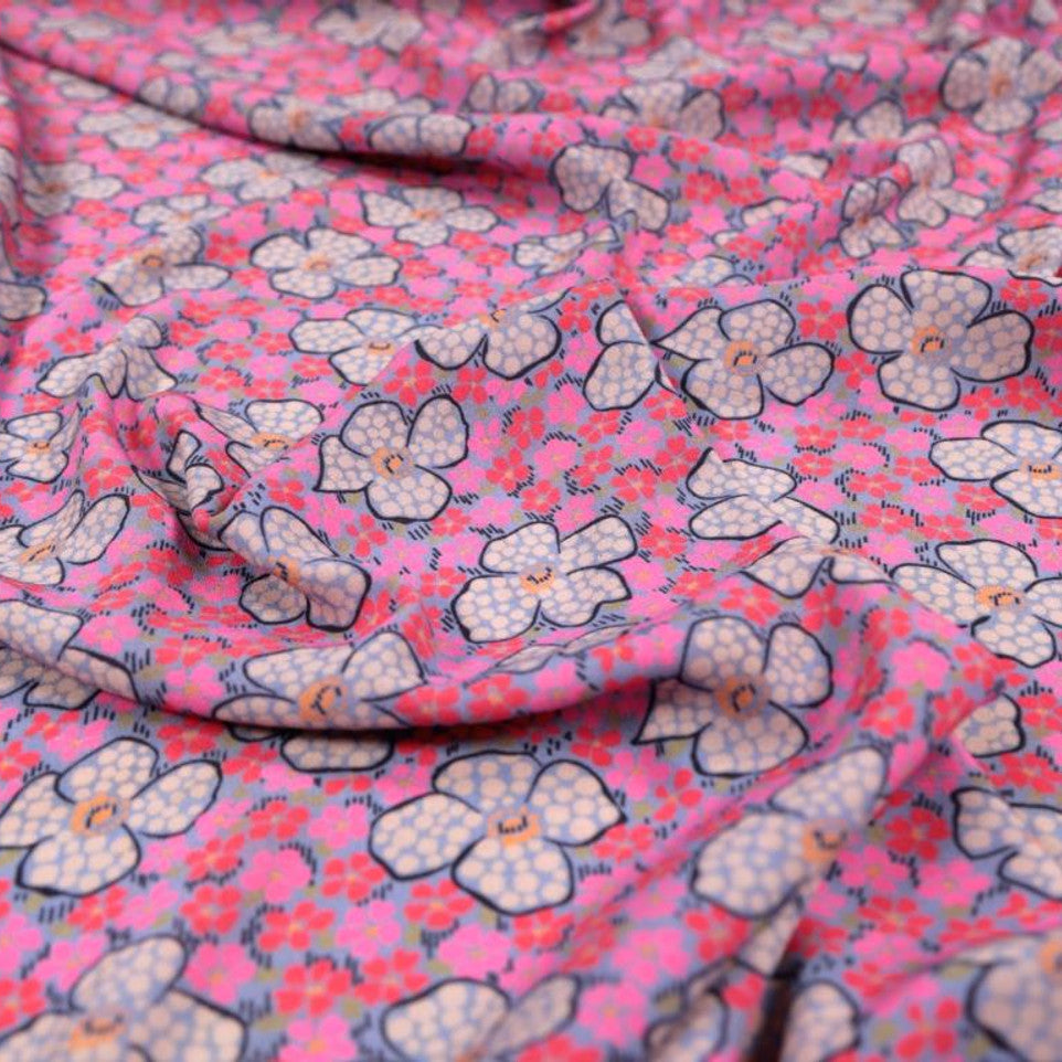 A woven viscose crepe fabric in pink with a floral pattern, sold by the half metre.