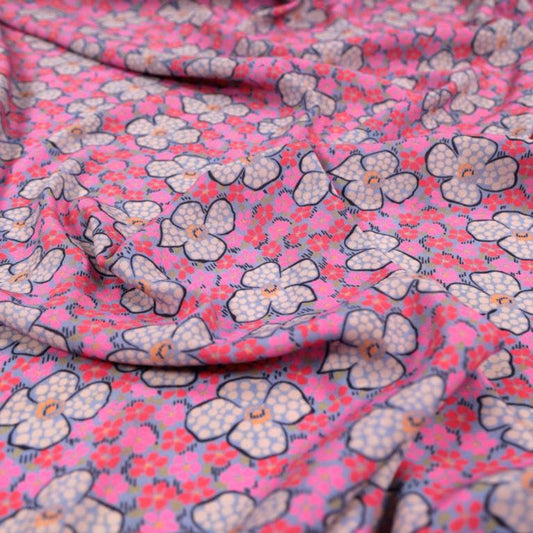 A woven viscose crepe fabric in pink with a floral pattern, sold by the half metre.