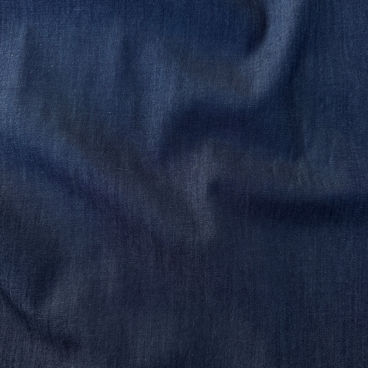 A close-up of dark navy blue fabric with a soft, slightly textured surface and gentle folds.