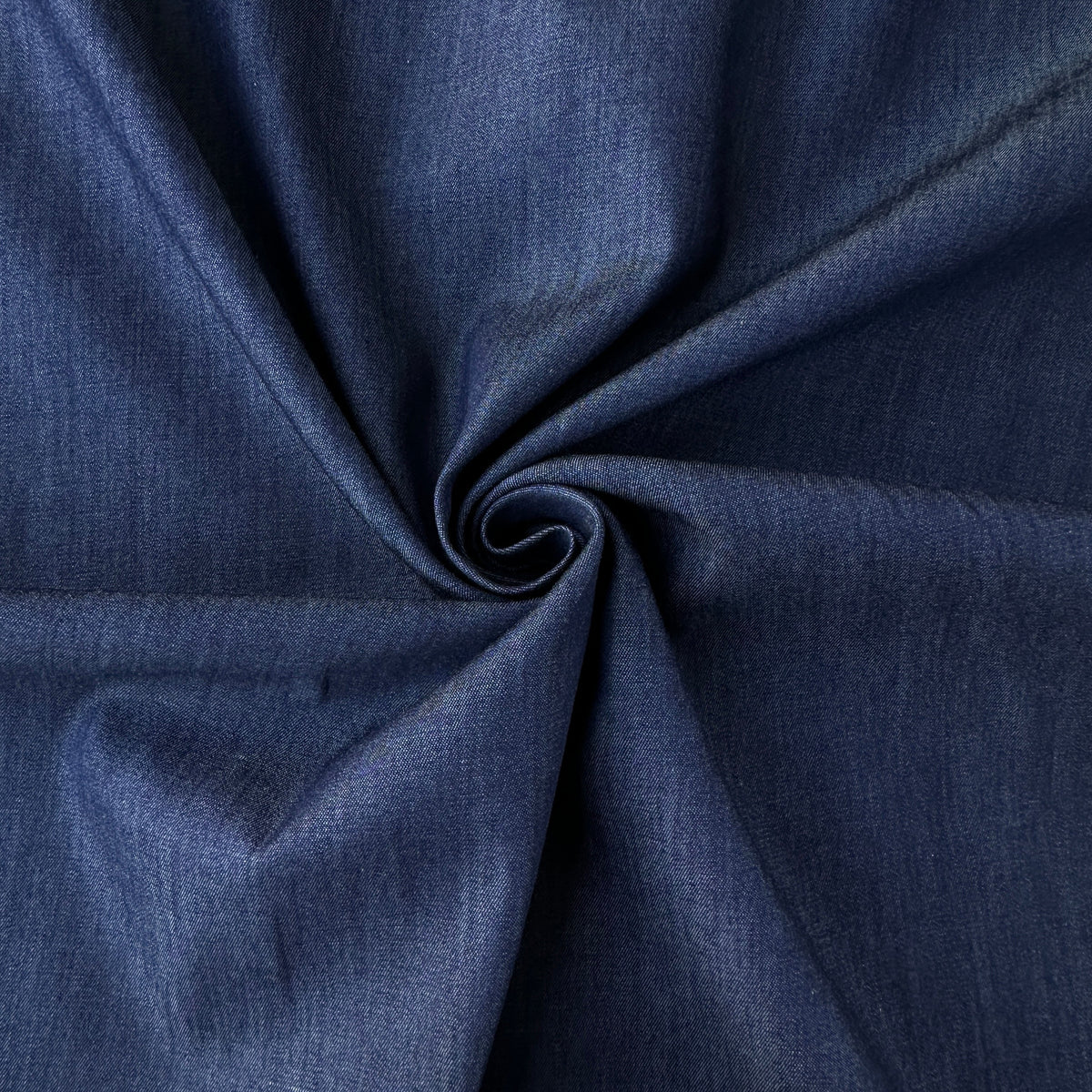 A close-up of dark blue fabric gathered into a spiral, showing its texture