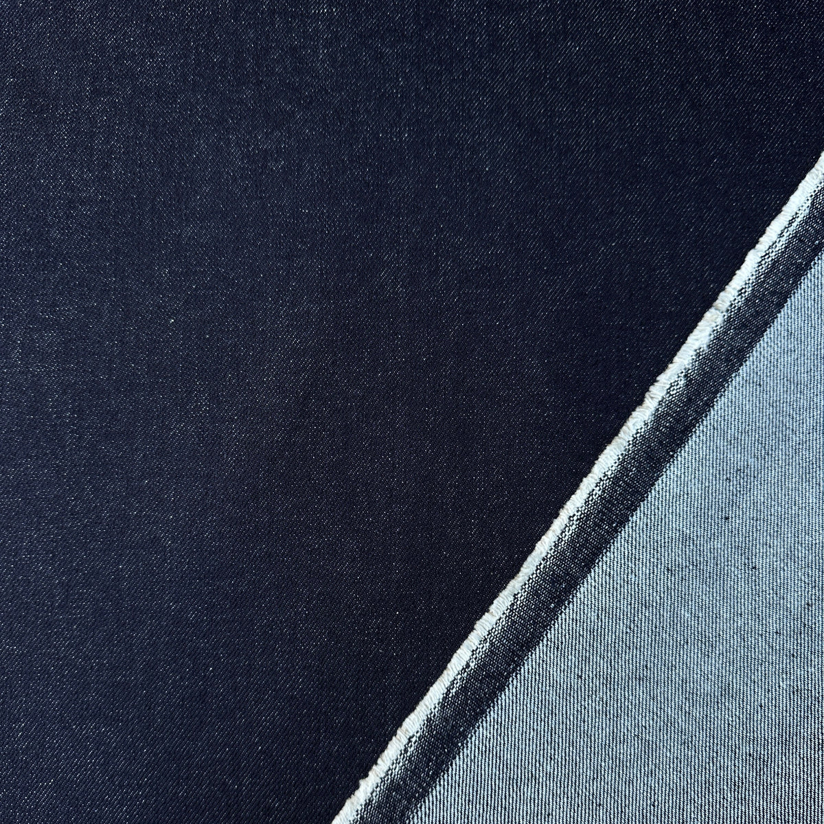 A close-up of a dark indigo fabric, with a folded corner showing the wrong side of the fabric