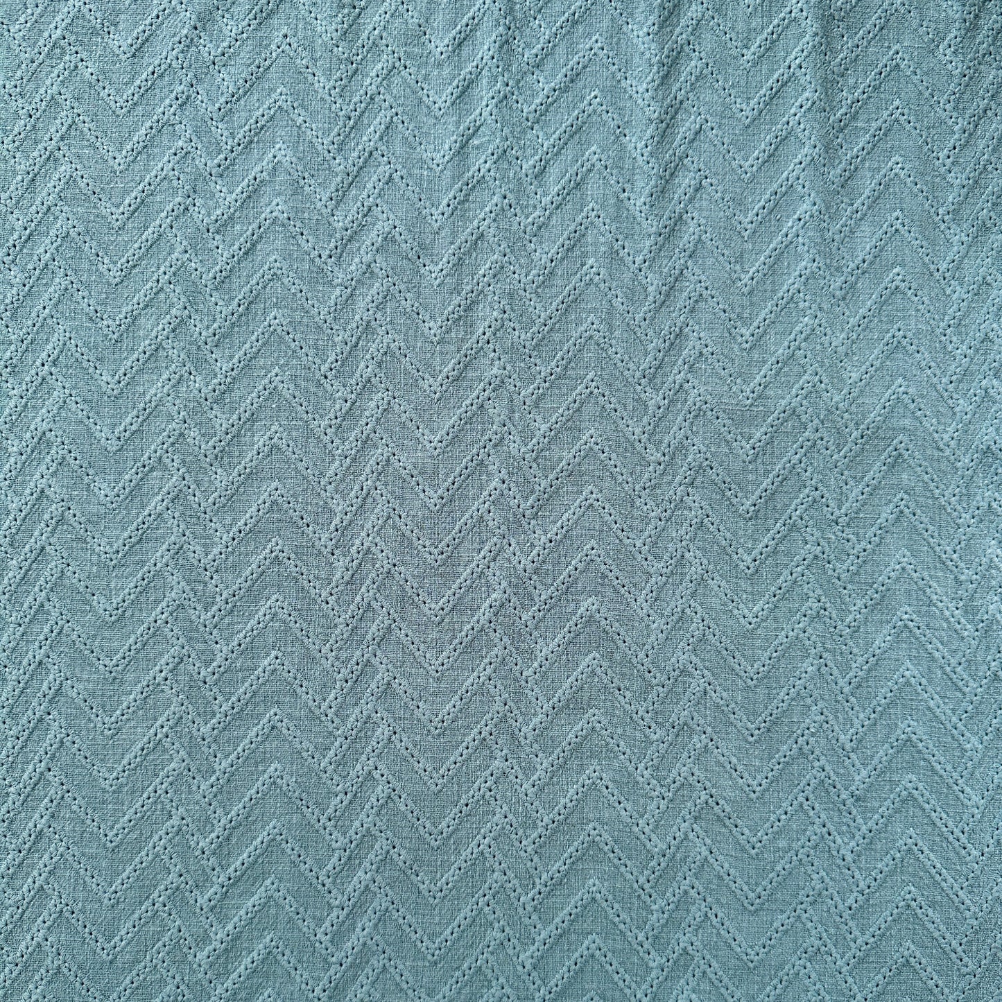 A close-up of a textured fabric with a zigzag pattern in blue
