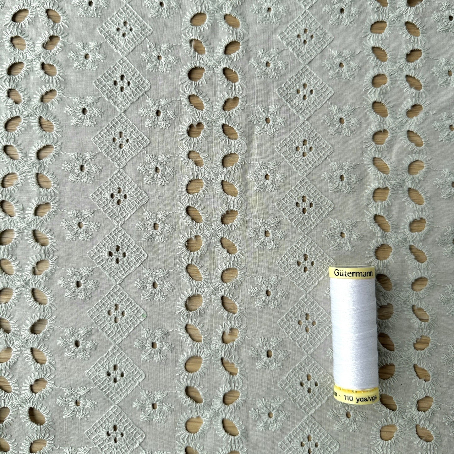 Embroidered cotton fabric with reel of thread for scale