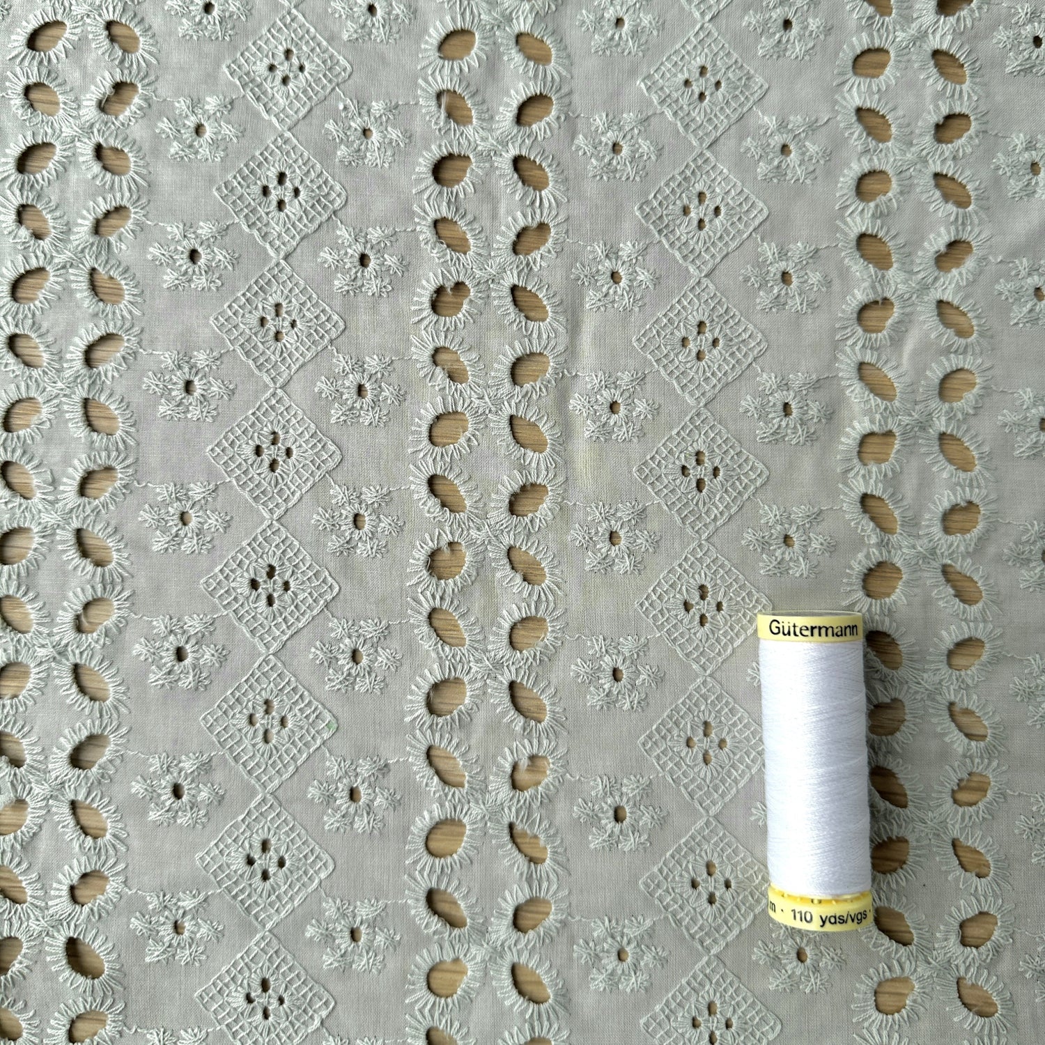 Embroidered cotton fabric with reel of thread for scale