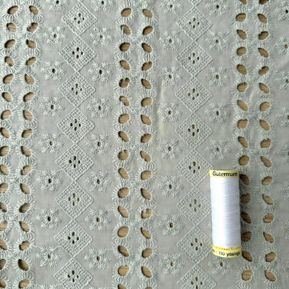 Embroidered cotton fabric with reel of thread for scale