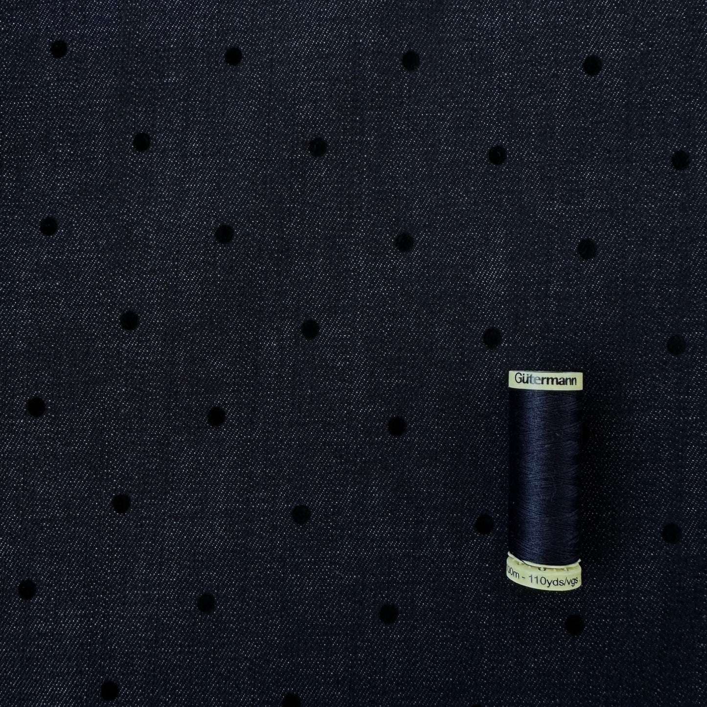 Reel of thread for scale on flocked polka dot indigo denim