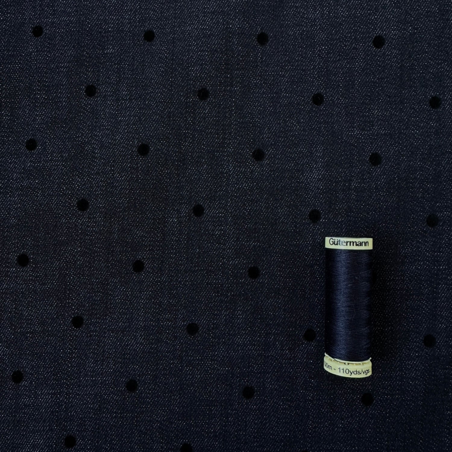 Reel of thread for scale on flocked polka dot indigo denim