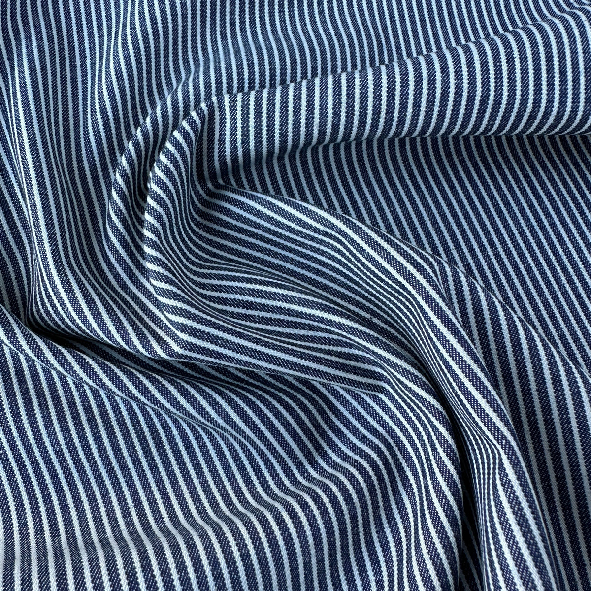 A close-up of draped fabric with a repeating vertical stripe pattern in navy blue and off white.