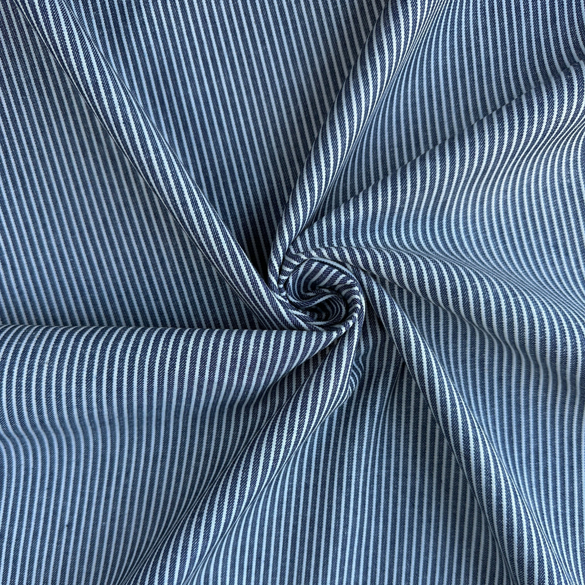 A close-up of blue and white vertically striped fabric, gathered in a spiral twist to show its drape and texture.