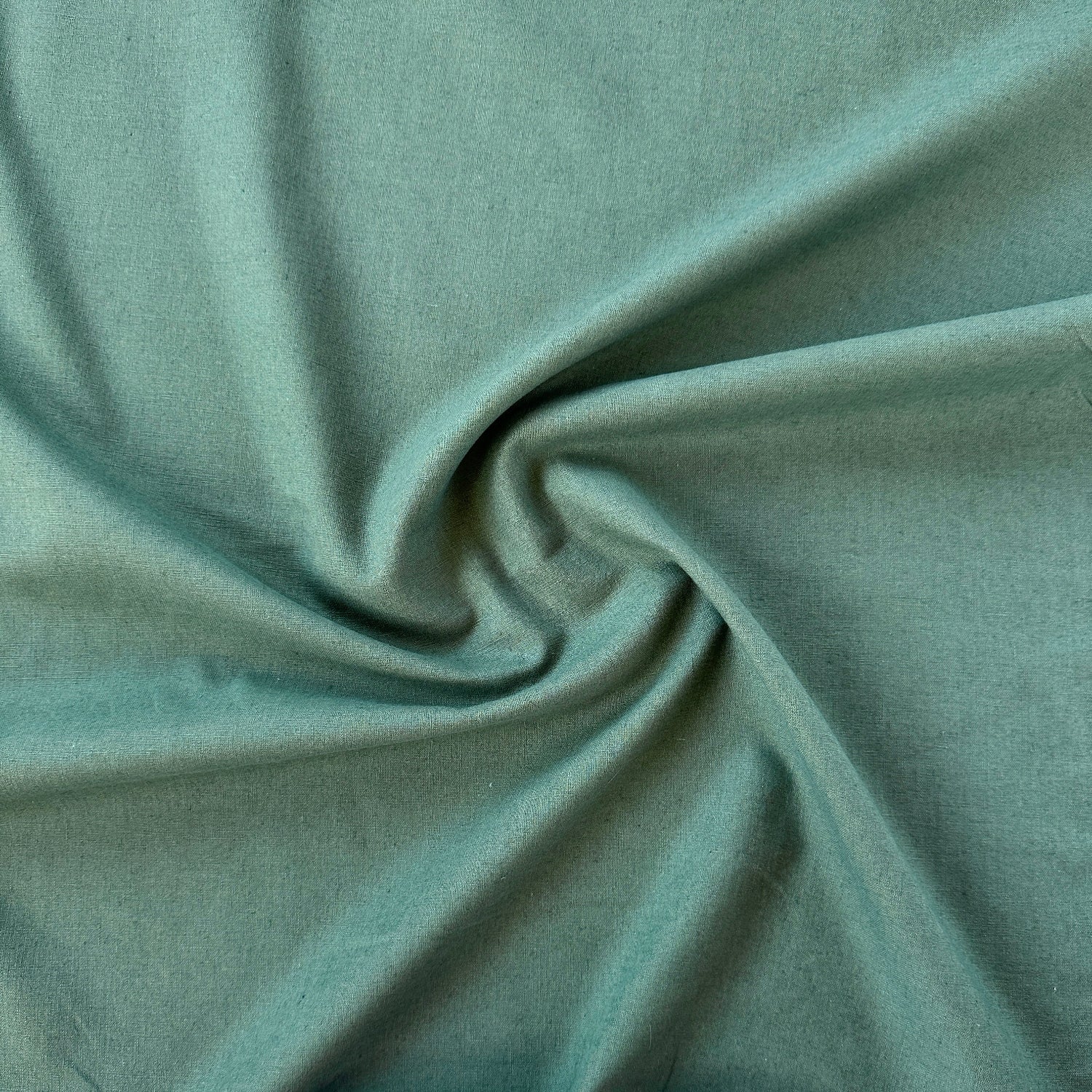 A close-up of draped sage green linen viscose blend fabric