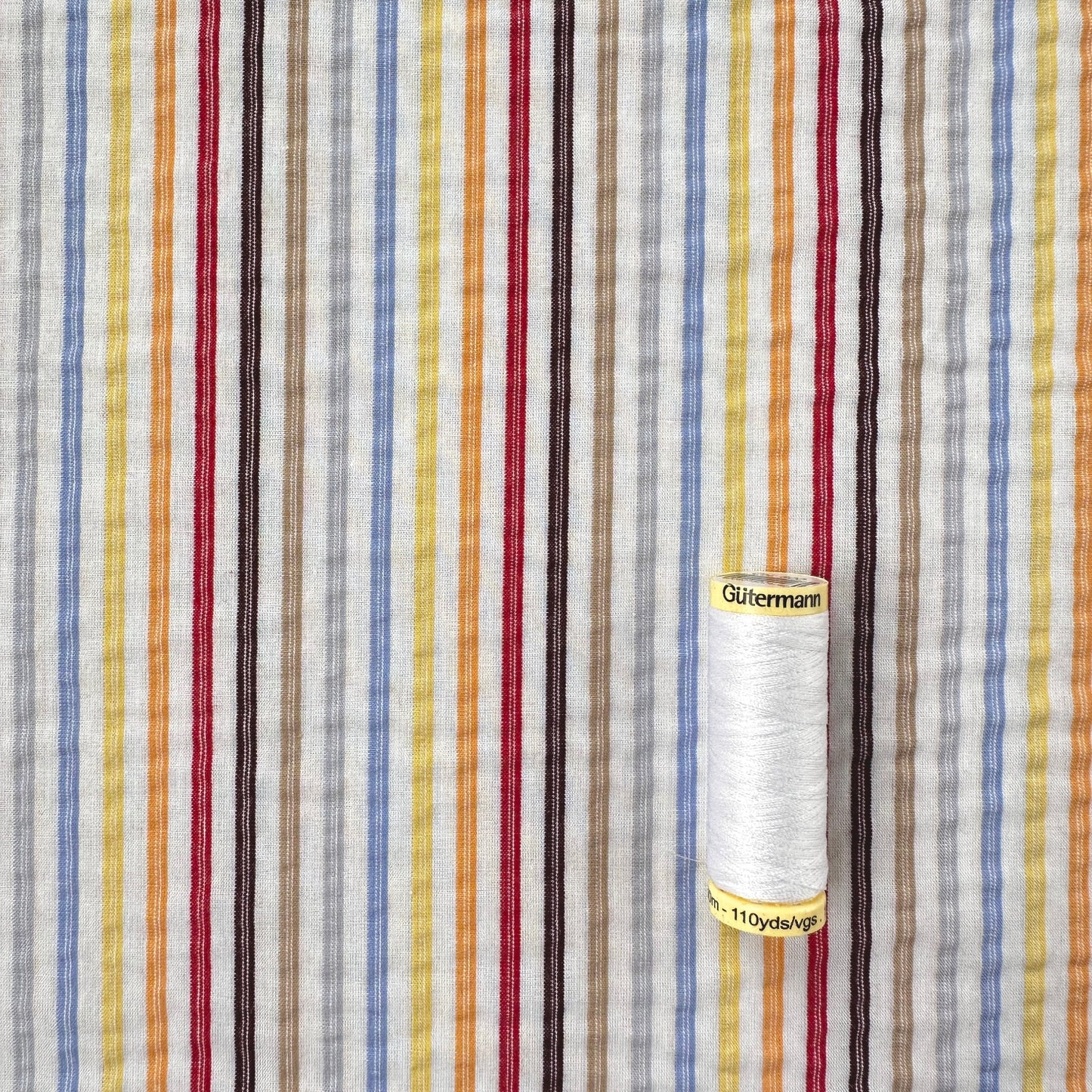Multi Colour stripe fabric with reel of Gutermann thread for scale