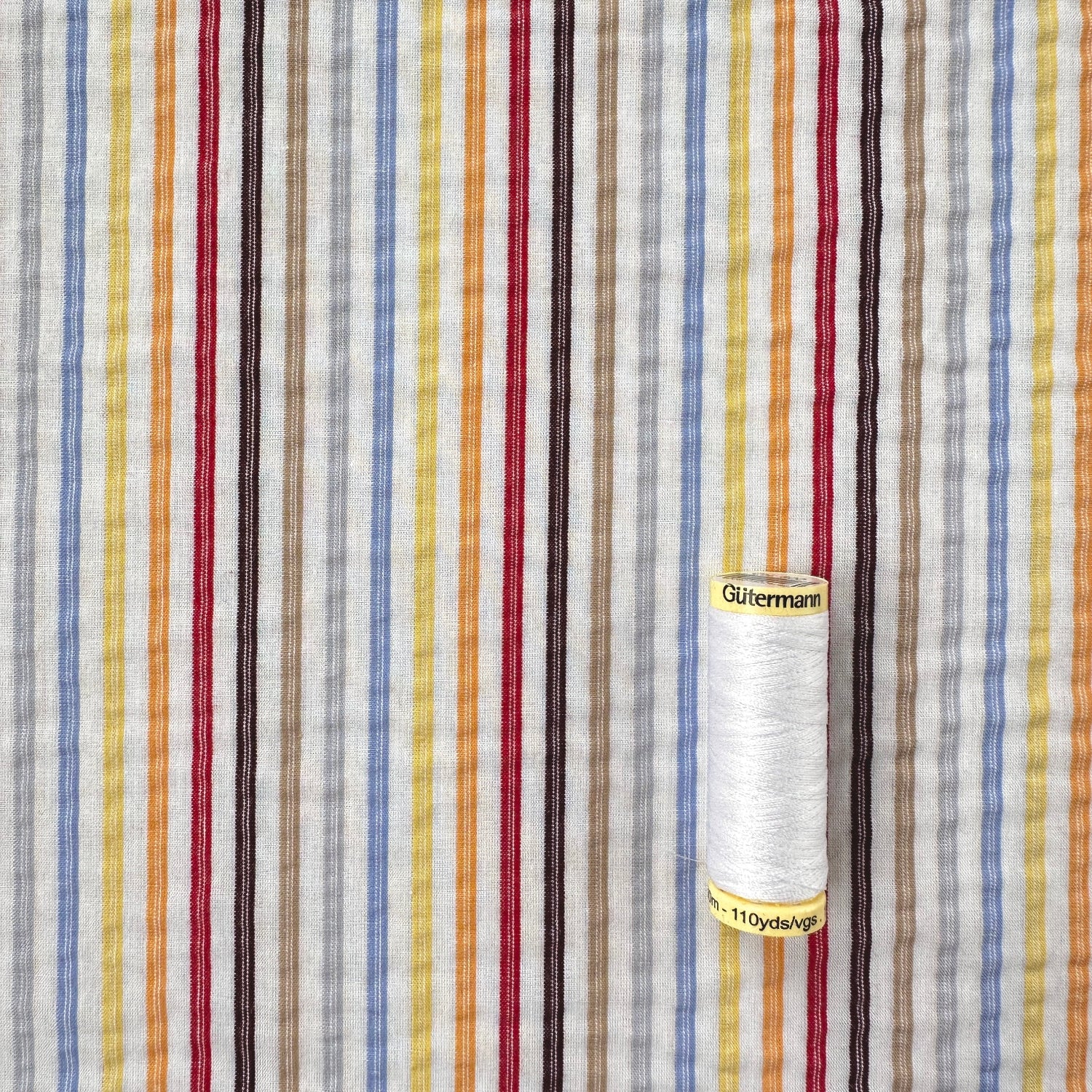 Multi Colour stripe fabric with reel of Gutermann thread for scale