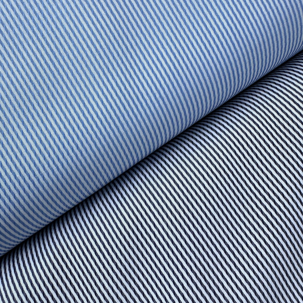 Close-up of two bolts of striped cotton dressmaking fabric, one in navy and white and the other in blue and white