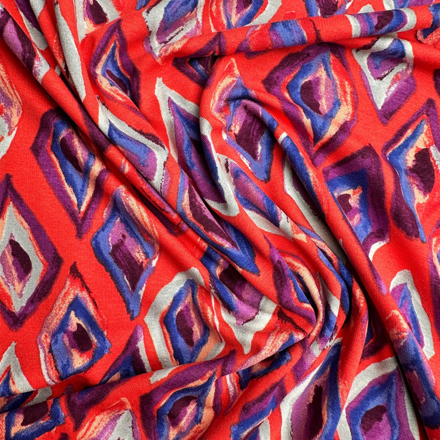 Viscose jersey fabric with geometric pattern in red, purple, and grey