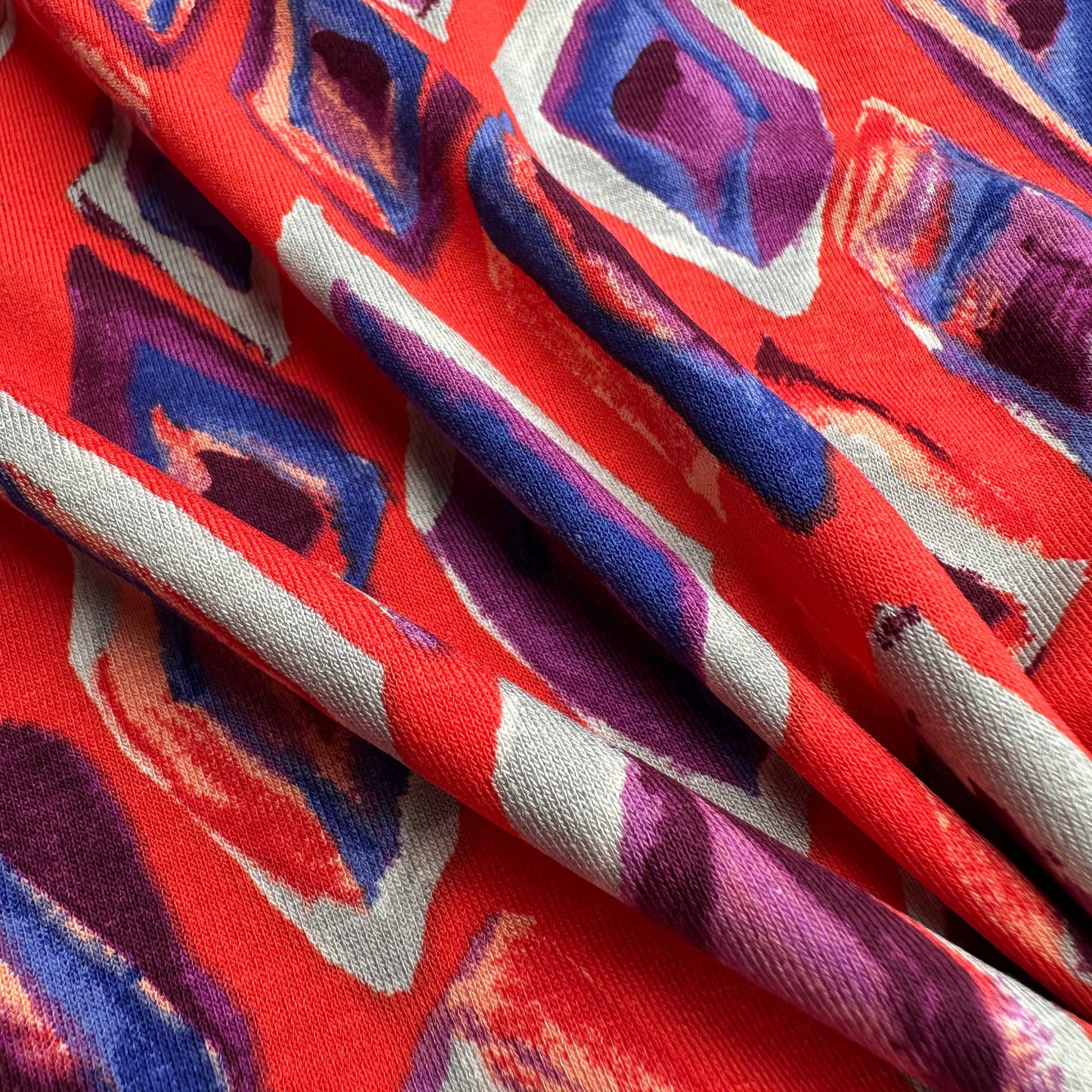 Close up of colourful fabric with geometric pattern on red background