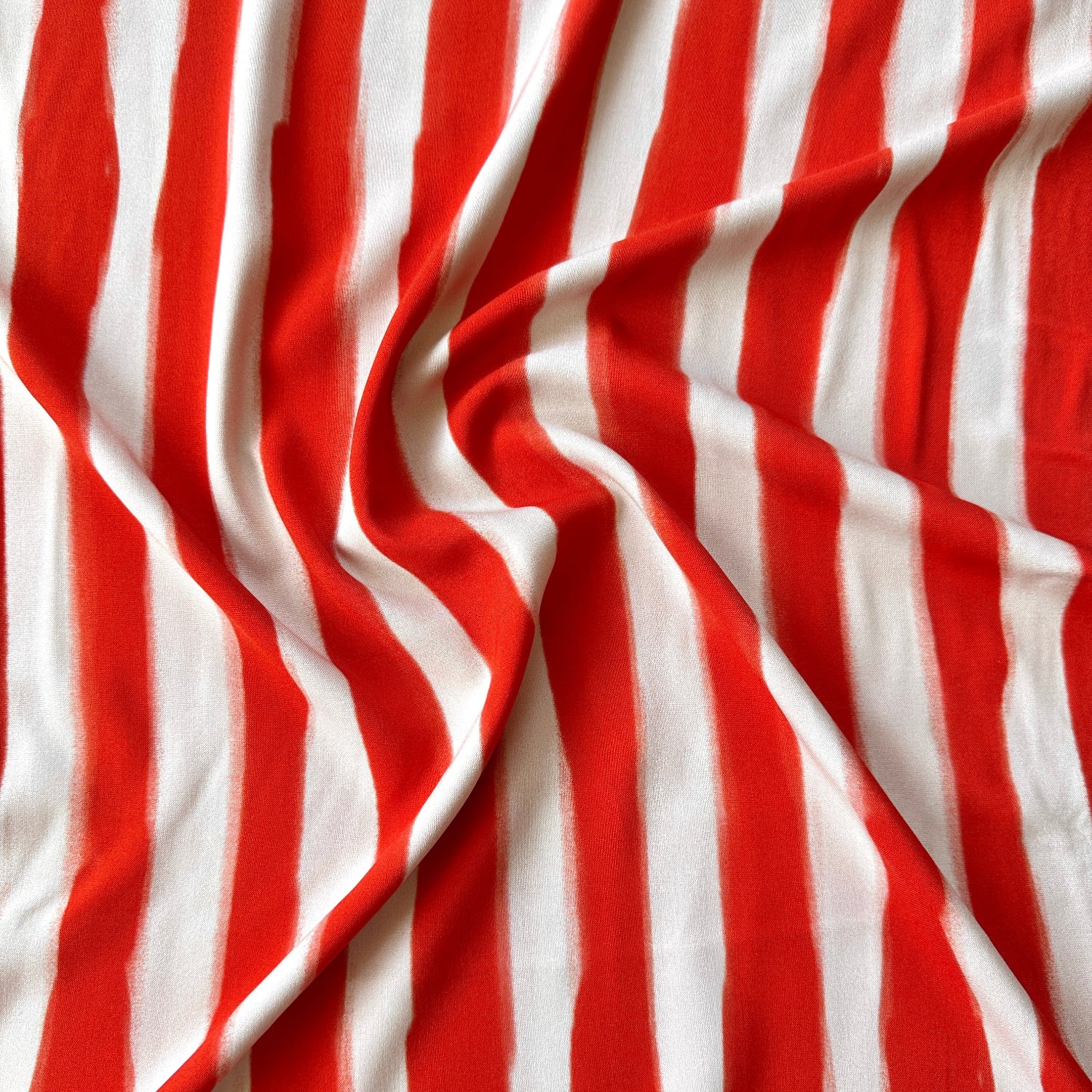 Red and white vertically striped fabric with a soft draped texture.