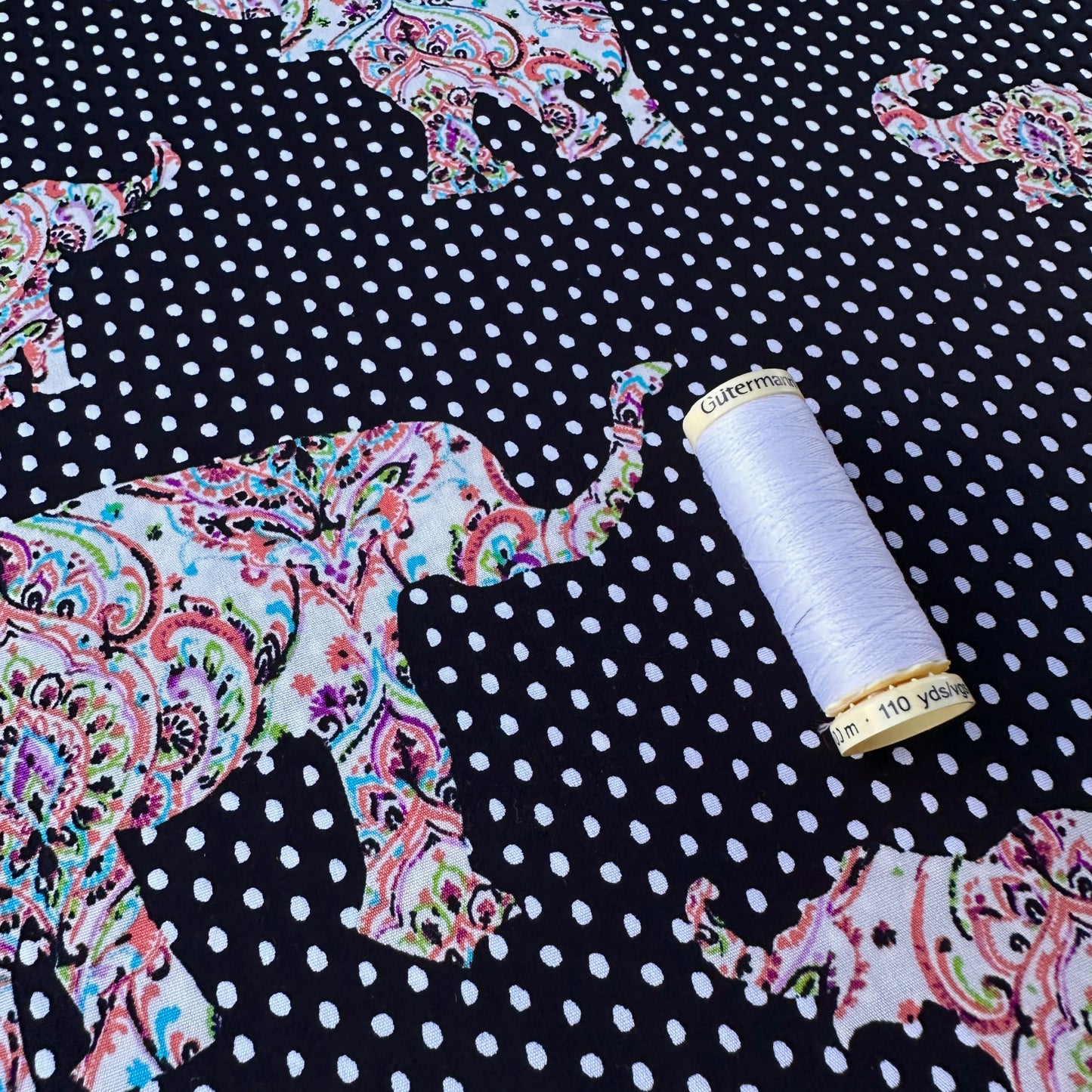 Paisley Elephants on Polka Dot Cotton Poplin Fabric With Reel of Thread for Scale