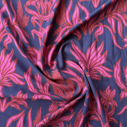 A swirl of viscose fabric in navy blue with pink and red flowers across it