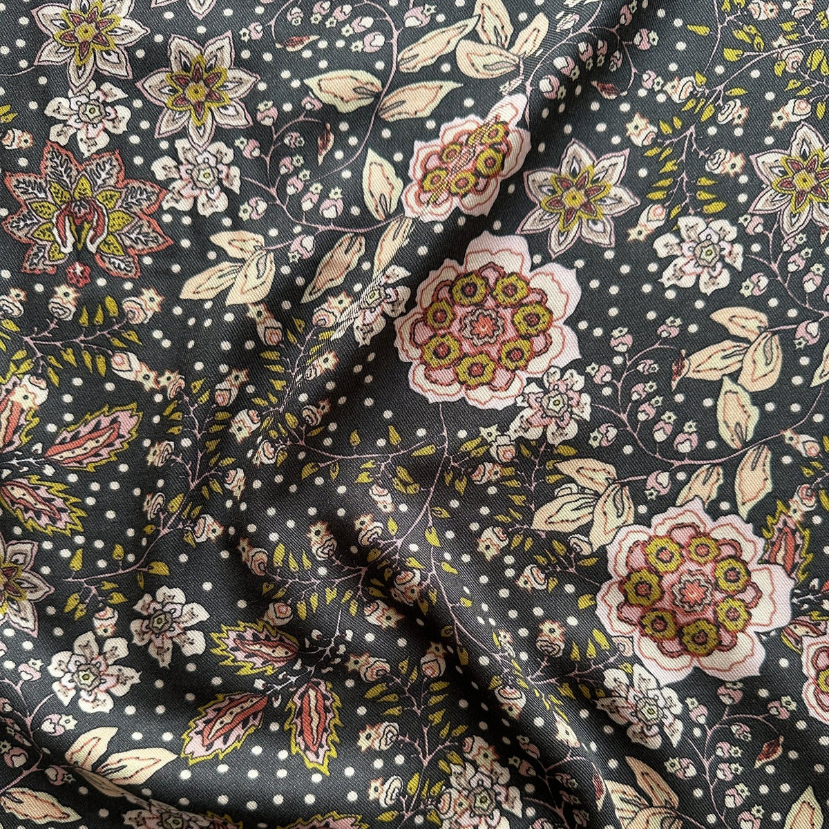 A fabric with a dark grey background featuring a floral design in lime green and pinks, folded to show both sides.