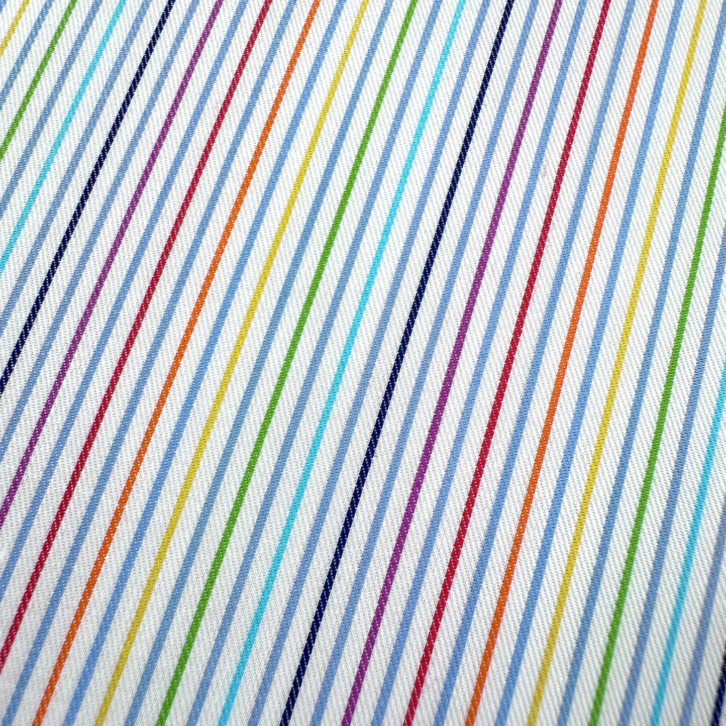 Close up of fabric with rainbow coloured pin stripes on a white background