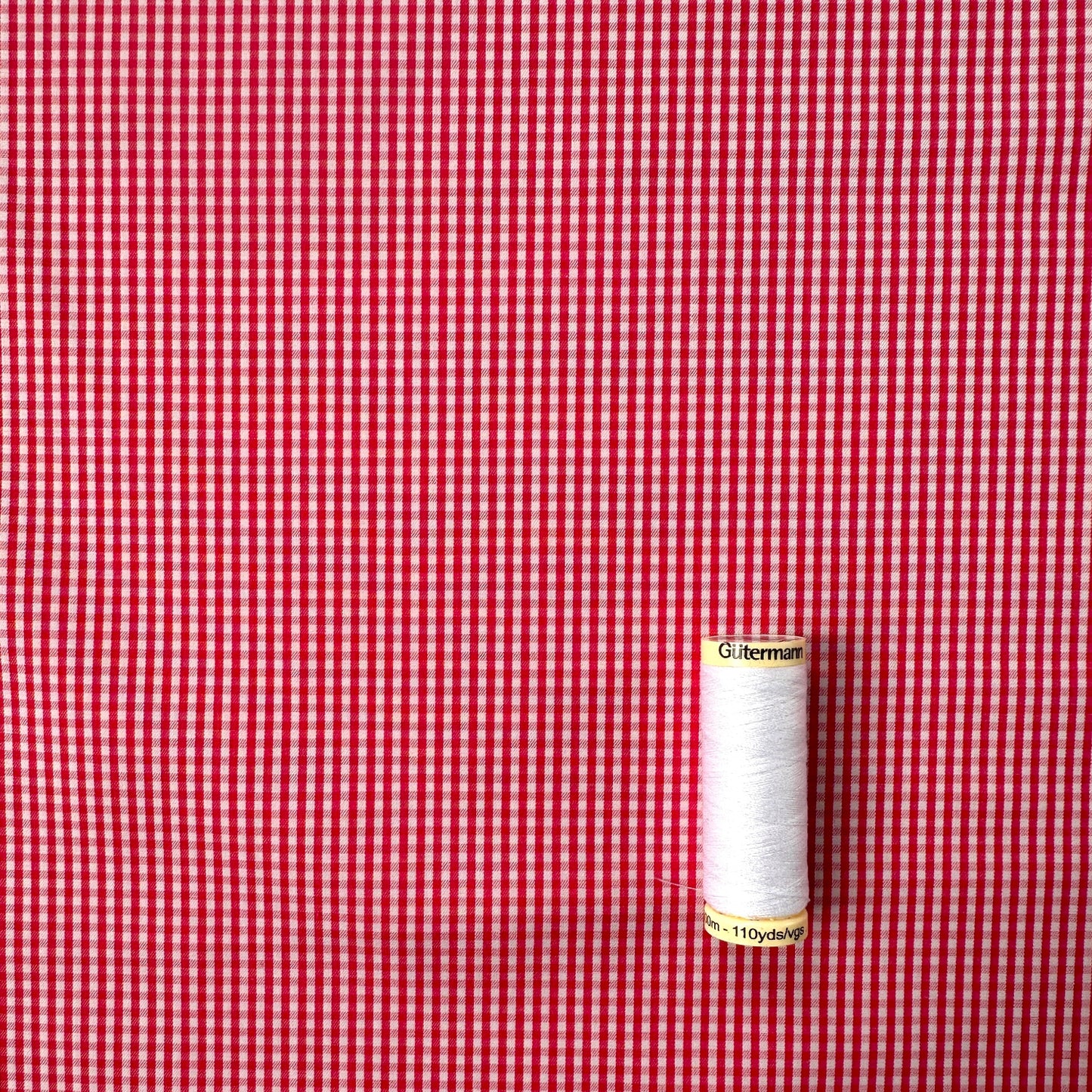 Reel of thread on a red and white checked fabric background