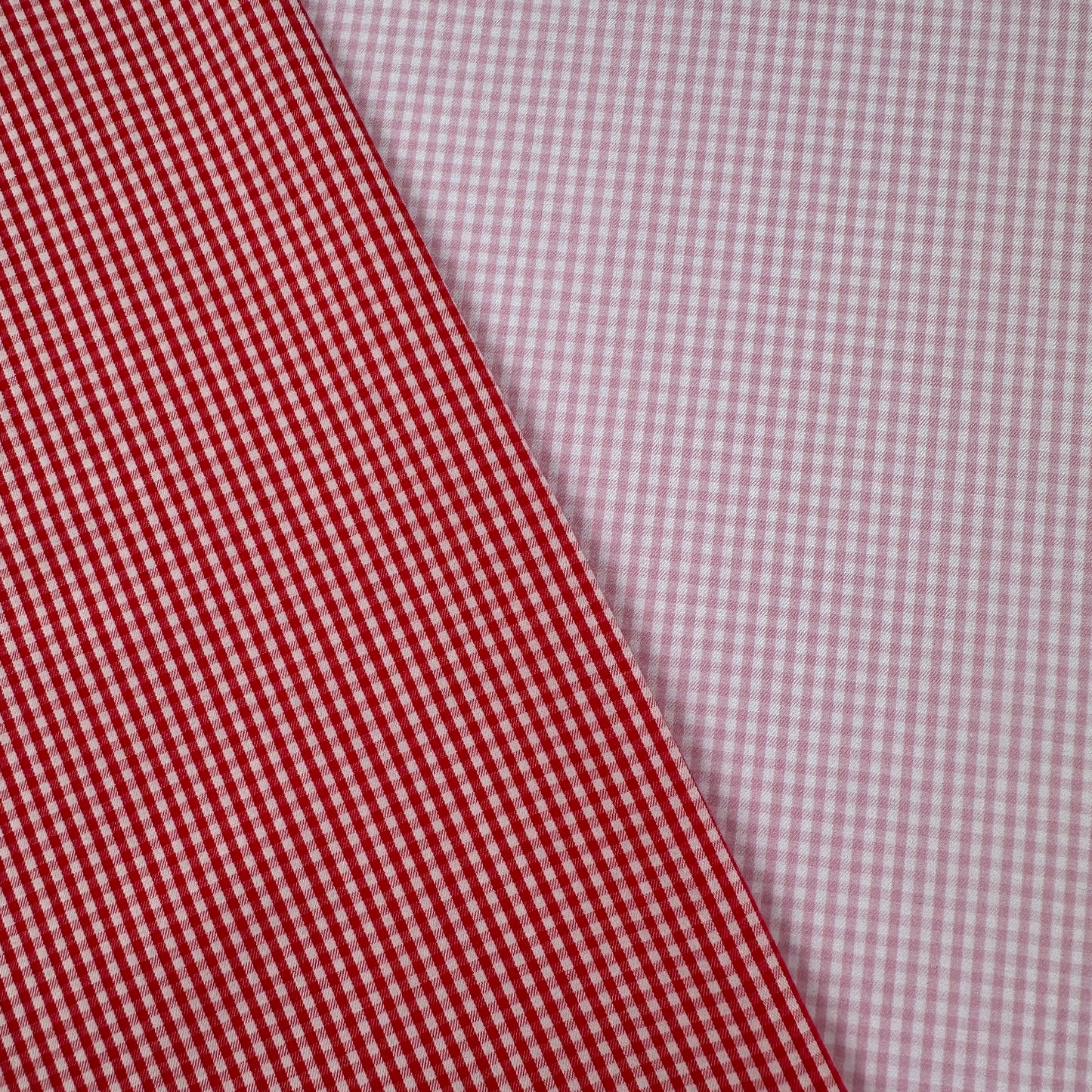 Two different checkered fabrics, one red and white, the other pink and white, on a diagonal.
