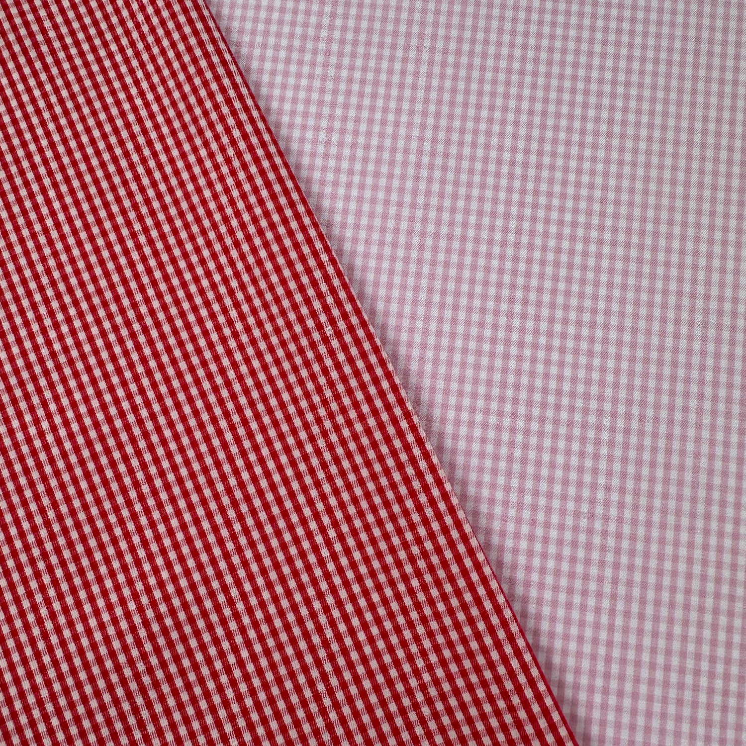 Two different checkered fabrics, one red and white, the other pink and white, on a diagonal.