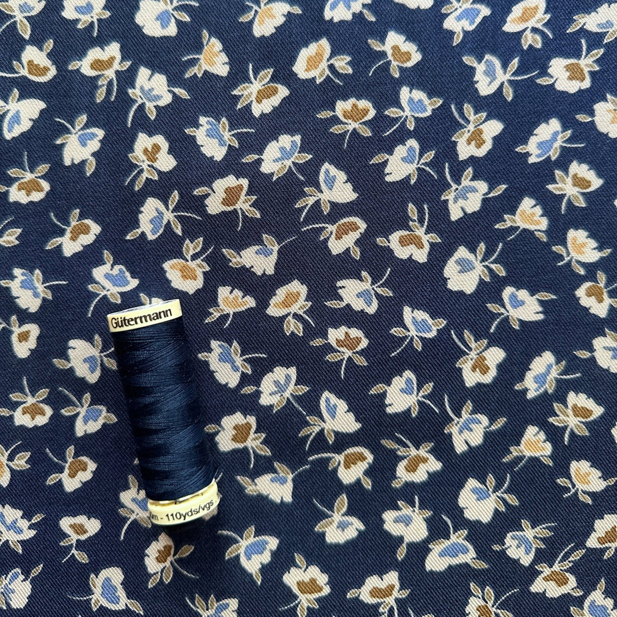 Reel of thread for sale of small flowers on navy viscose twill fabric