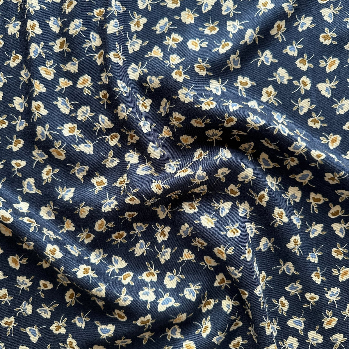 soft folds of navy viscose twill fabric with small flowers across it