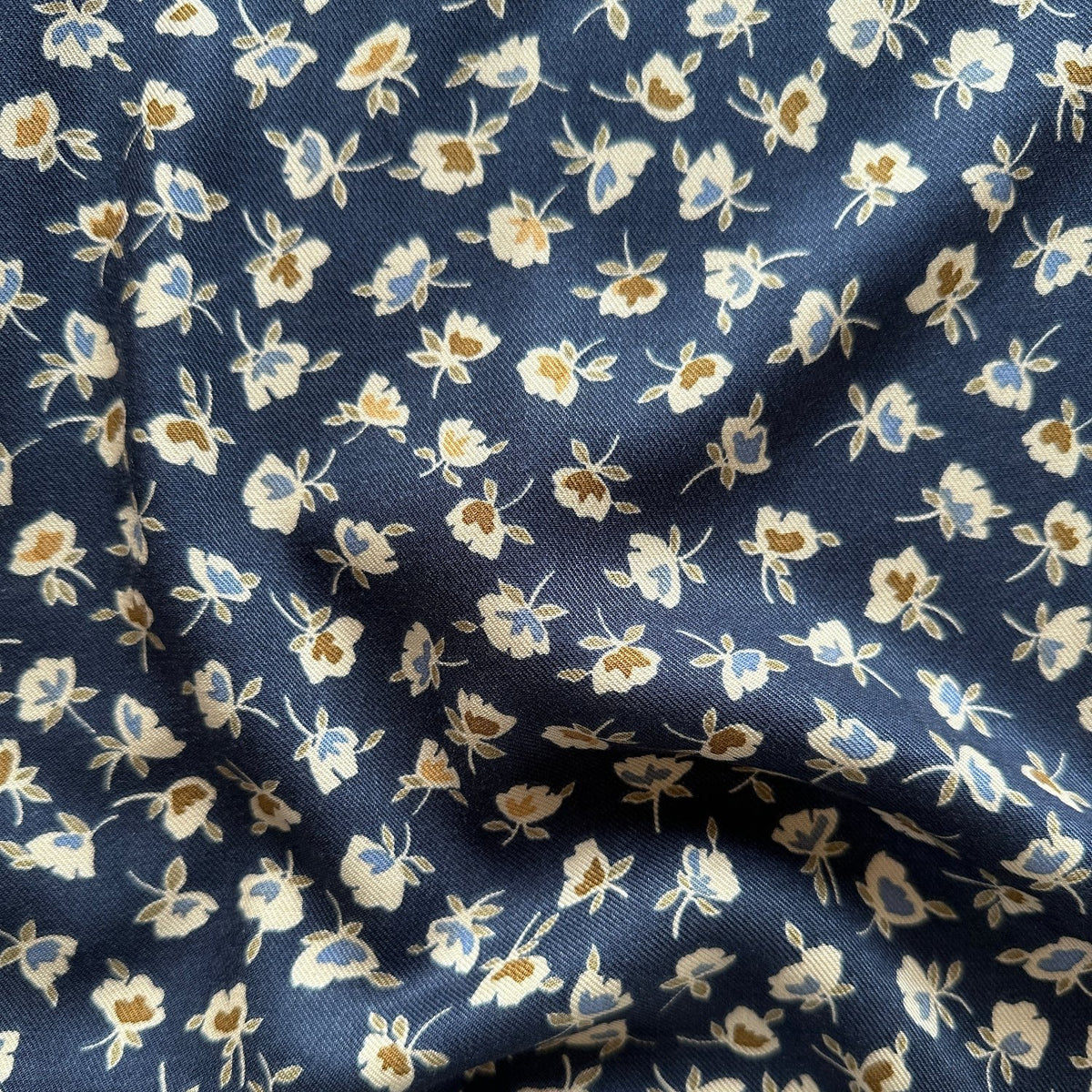 Viscose twill dressmaking fabric with a navy background and small flowers across it.